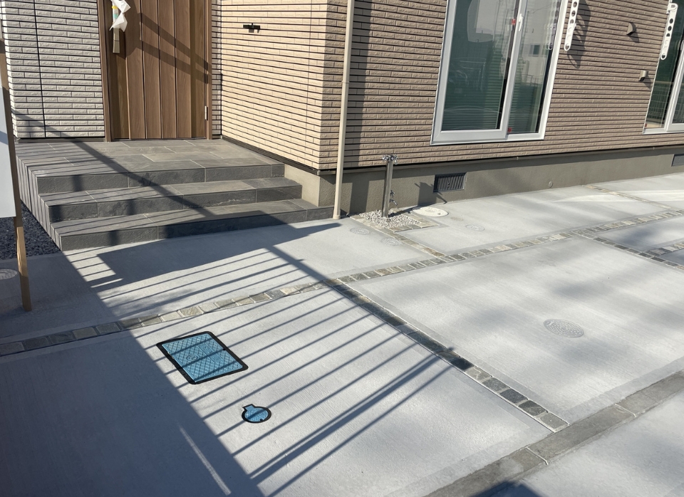 埼玉県川越市U様邸の外構工事完成写真。玄関前から続く土間コンクリートに100角天然石をライン状に配置し、シンプルながらも上品に仕上げた外構デザイン。